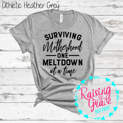 Surviving Motherhood One Meltdown At A Time Graphic T-Shirt | Funny Mom Tee | Boutique Mama Shirt | Relatable Mom Graphic Tee | Motherhood Shirt