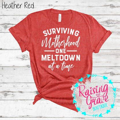 Surviving Motherhood One Meltdown At A Time Graphic T-Shirt | Funny Mom Tee | Boutique Mama Shirt | Relatable Mom Graphic Tee | Motherhood Shirt